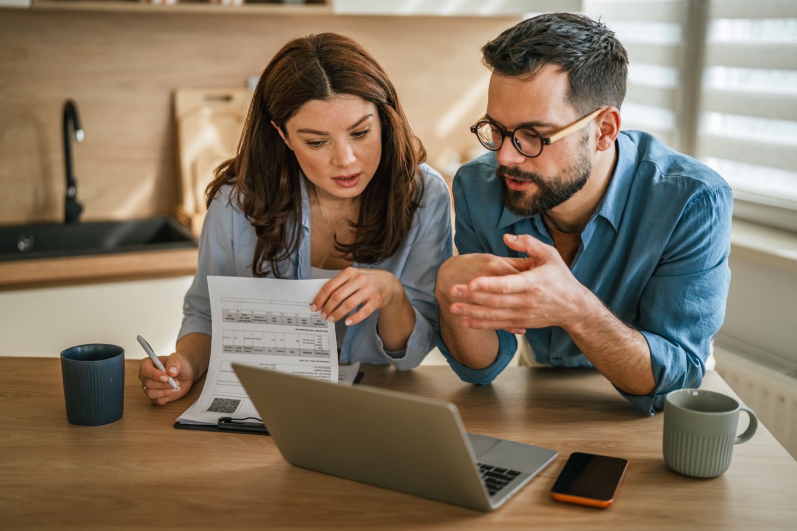 Two professionals reviewing shipping data and documents together at a desk with a laptop